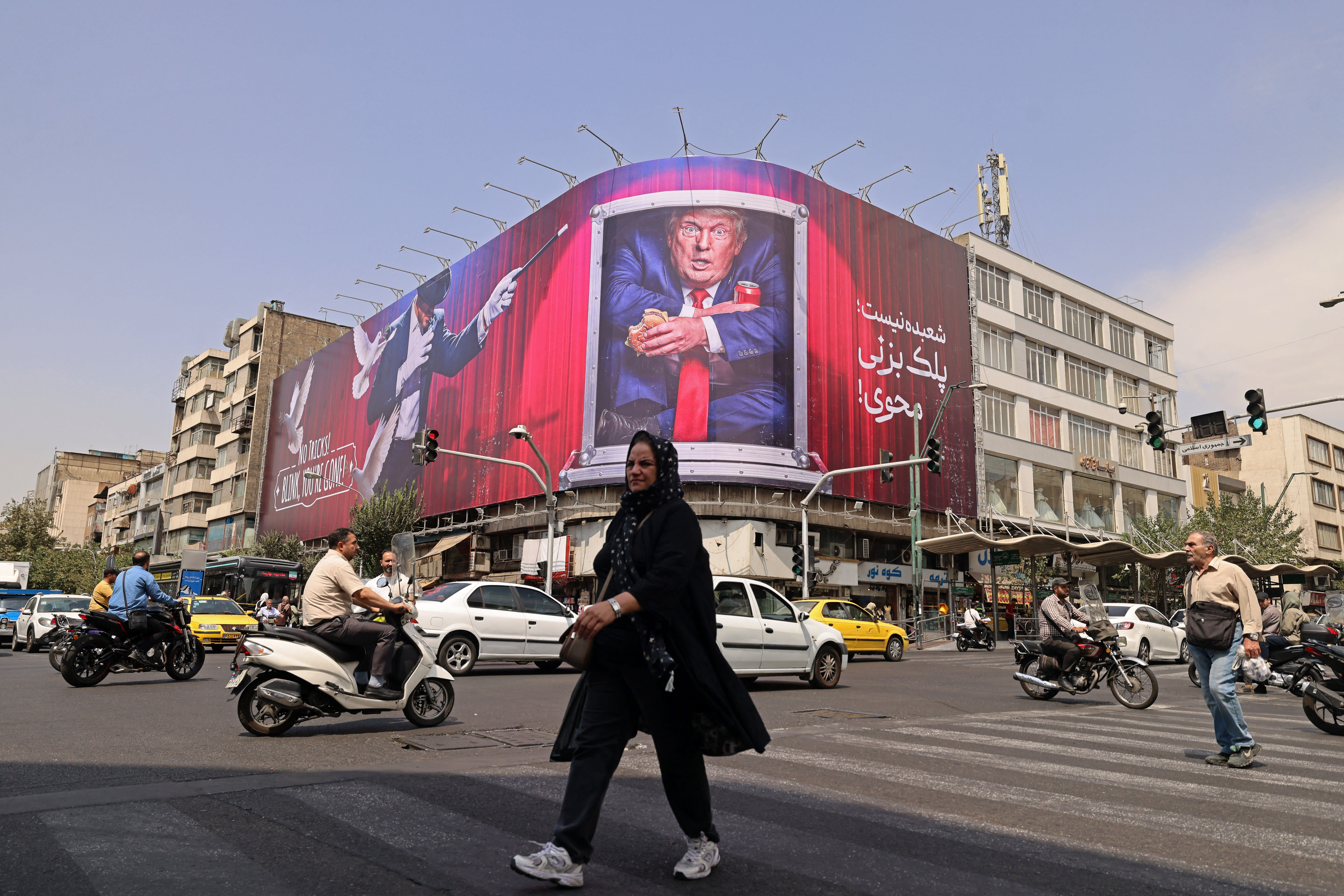 A pedestrian walks past a billboard depicting US President Donald Trump inside a catering container, installed on a building along a street in downtown of Tehran on August 31, 2026. (photo credit:  ATTA KENARE / AFP via Getty Images)