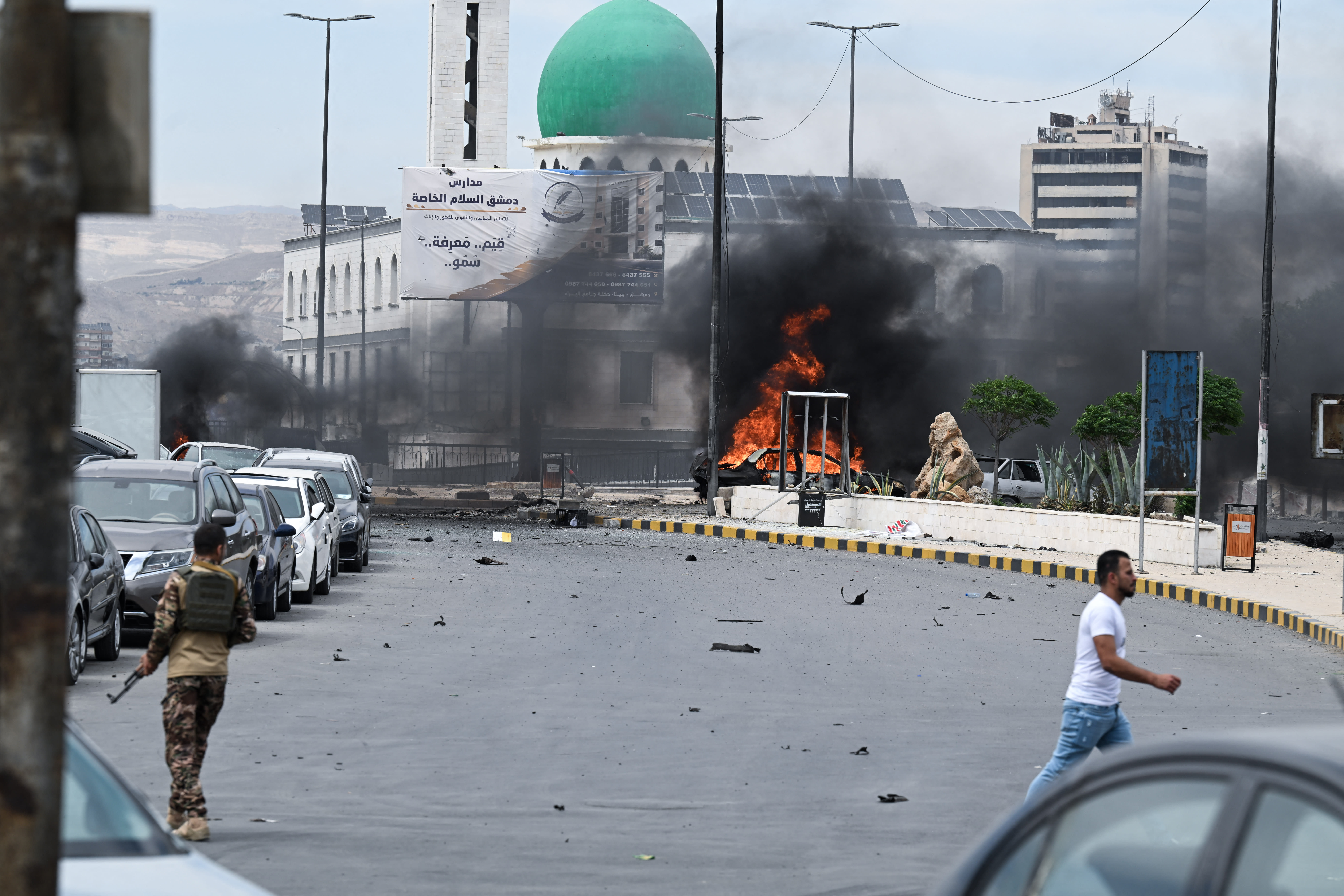 A member of the security personnel arrives at the scene near a burning vehicle following an explosion in Damascus on May 19, 2026. (photo credit: AFP VIA GETTY IMAGES)