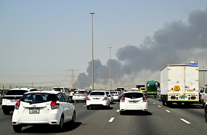Smoke billows from an ongoing fire near Dubai International Airport as vehicles drive on a highway in Dubai on March 16, 2026. (photo credit: AFP VIA GETTY IMAGES)