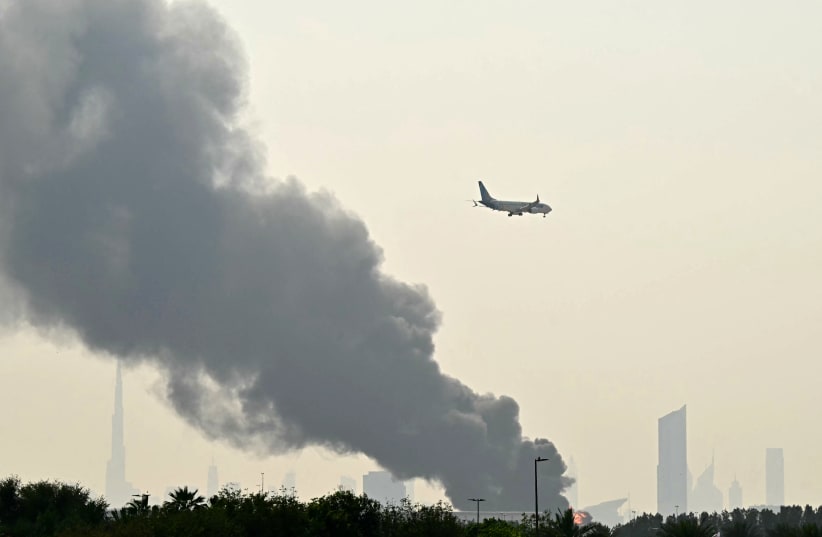 Illustrative; An Emirates aircraft flies past plumes of smoke from an ongoing fire near Dubai International Airport in Dubai on March 16, 2026.