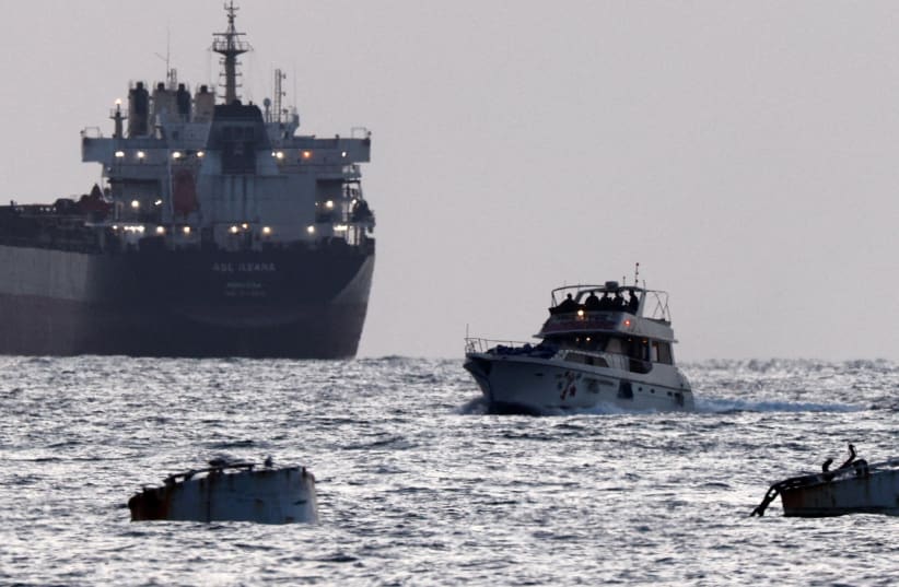 Israeli soldiers are seen on a vessel bearing symbols of the Global Sumud Flotilla, with a cargo ship behind it, as seen from Ashdod, southern Israel, May 19, 2026. 