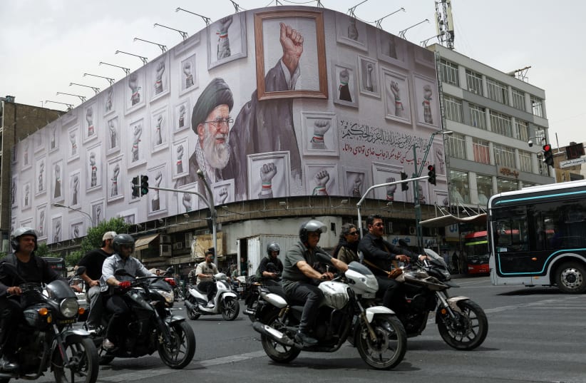 PEOPLE RIDE motorcycles near a billboard with an image of the late Iranian Supreme Leader Ayatollah Ali Khamenei, in Tehran, Iran, May 19, 2026.