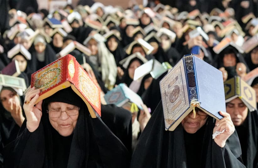 Shiite Muslim devotees sit in prayer while having copies of the Koran, Islam's holy book, placed on the head as they attend mass prayers.