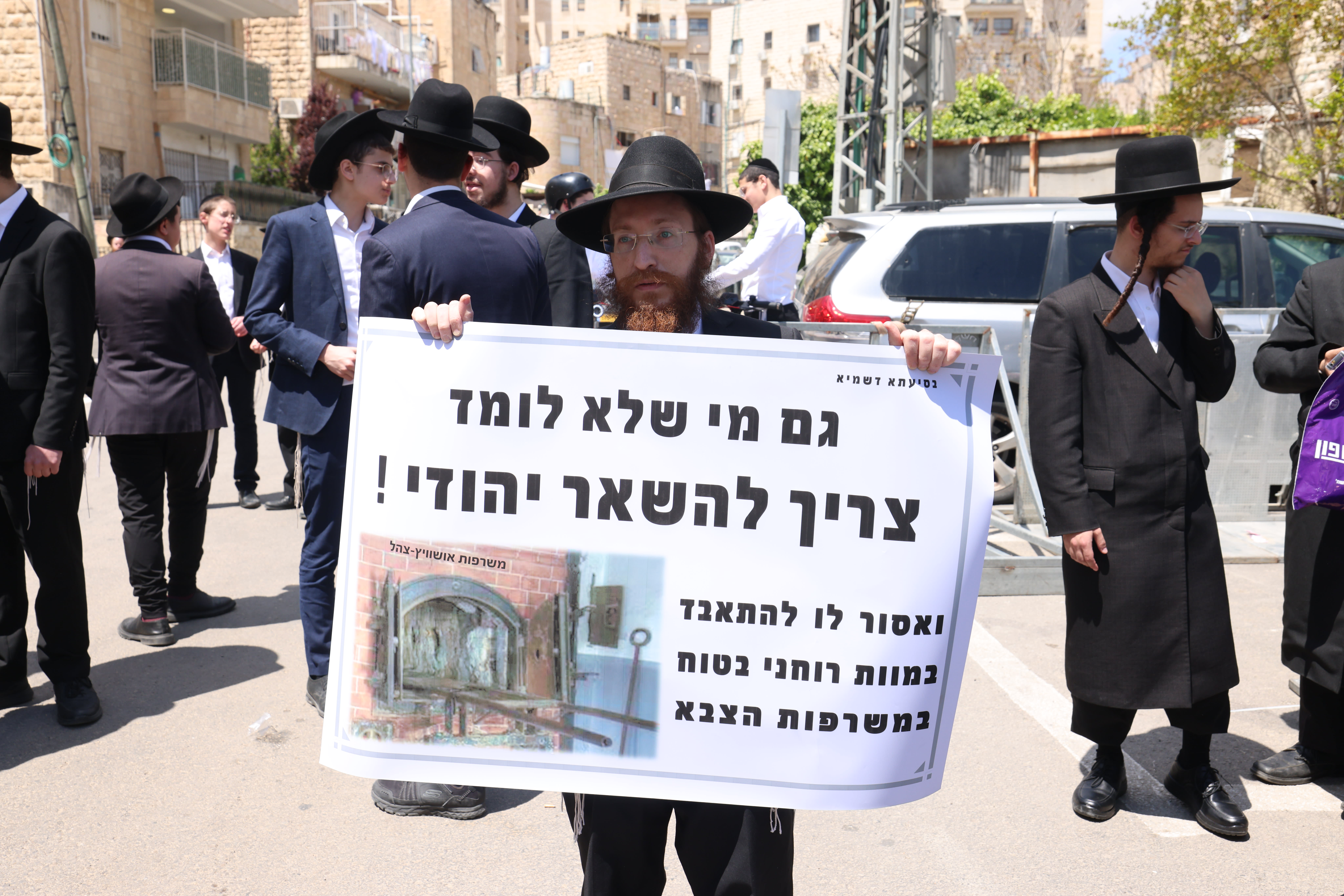 A haredi (ultra-Orthodox) anti-draft protester holds a banner reading "Even those who do not learn in Yeshiva need to stay Jewish. It