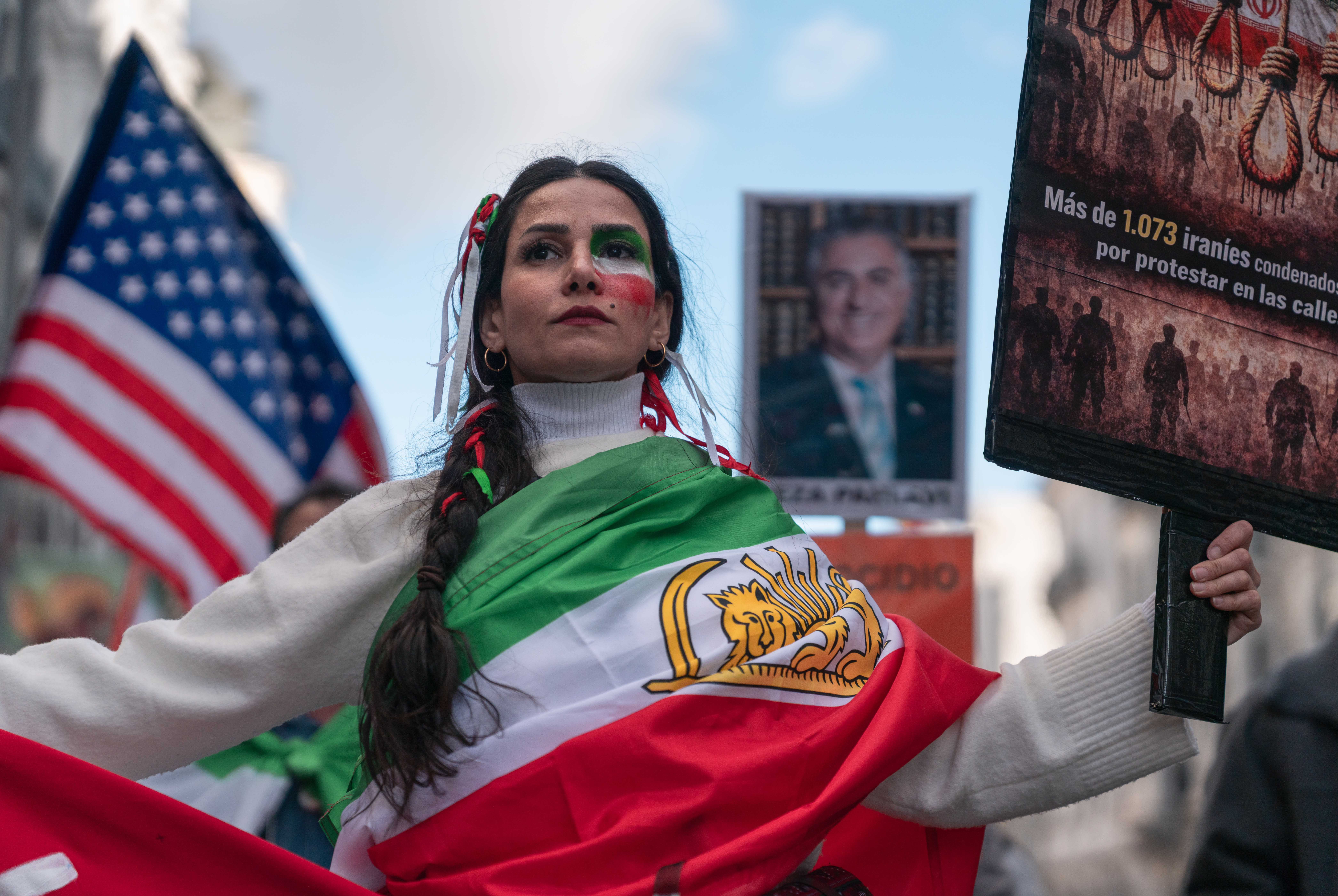 A woman wearing a Lion and Sun Iranian flag (used before the 1980 Islamic Revolution) holds a sign during a protest in solidarity with the anti-government protesters of Iran on February 14, 2026. (photo credit:  Olmo Blanco/Getty Images)