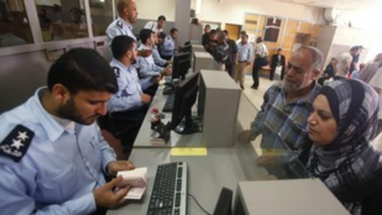 Hamas policeman checks passport at Rafah border 311 (R)