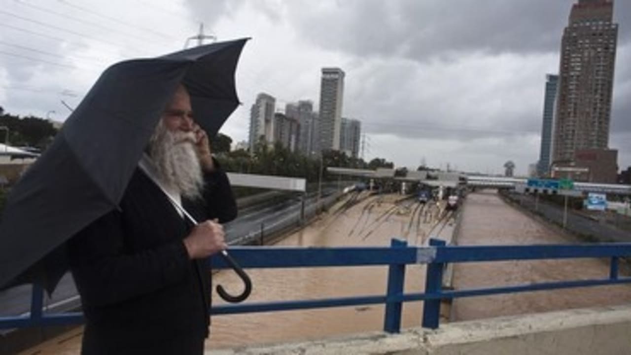A man stands on a bridge overlooking flooded railway tracks