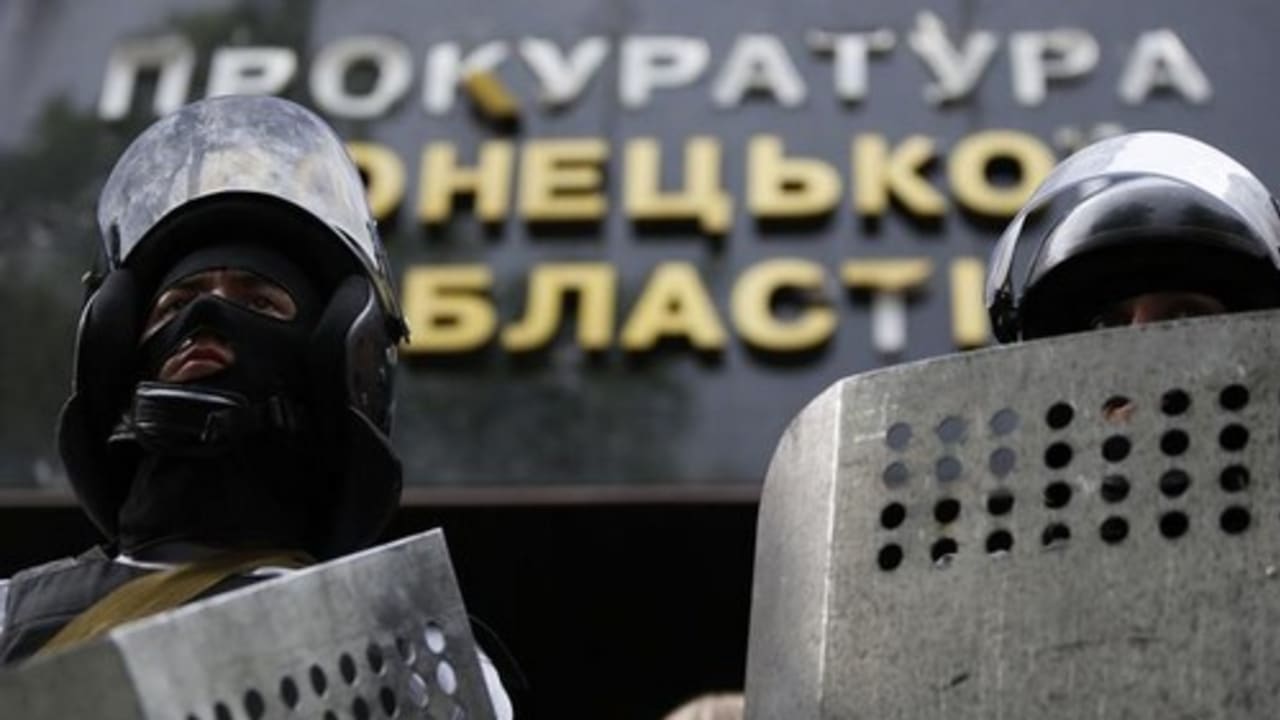 Pro-Russia activists wearing riot police helmets and shields stand guard at the entrance of the prosecutor's office in Donetsk May 1, 2014