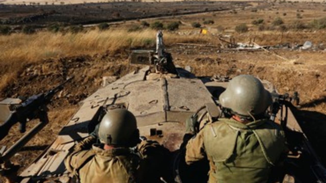 SOLDIERS SIT atop a tank as they watch the border with Syria near Quneitra
