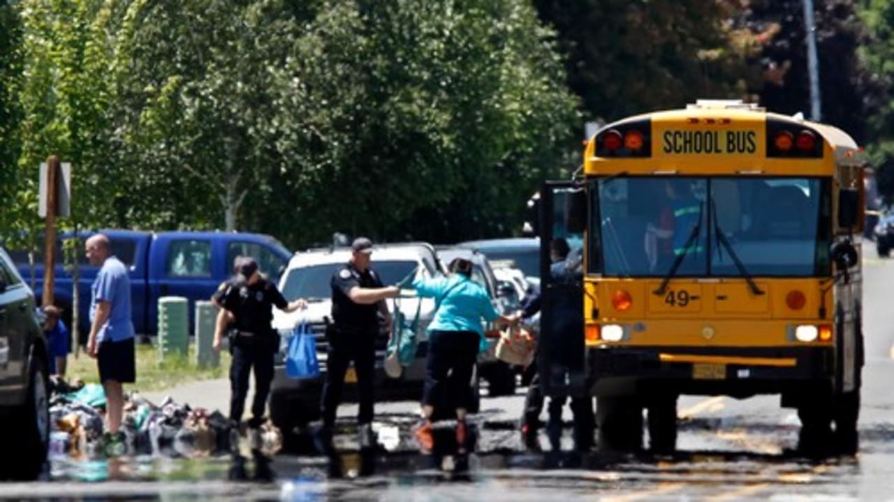 Police transfer student backpacks into a school bus after a shooting at Reynolds High School in Troutdale, Oregon June 10, 2014