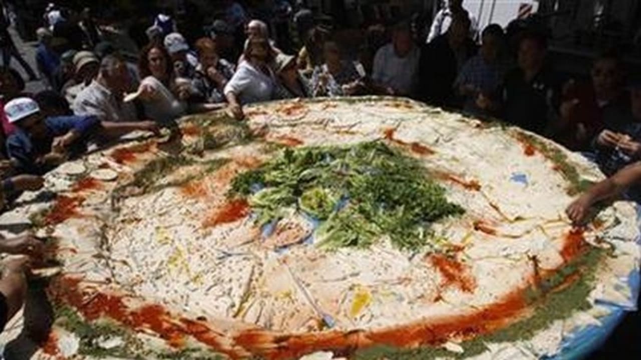 People stand around a large plate of hummus in Jerusalem, May 5, 2008.