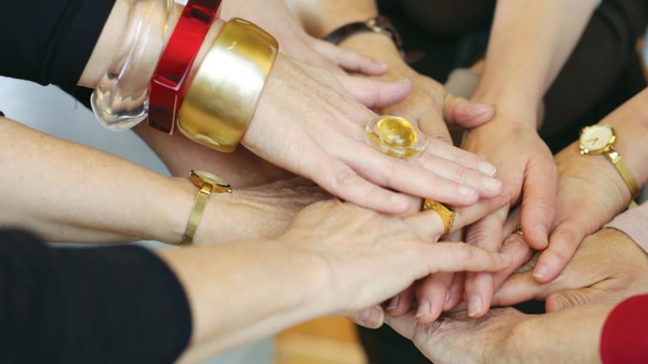Woman who are part of the ‘One in Nine’ breast cancer awareness group, put their hands together at the end of an exercise.