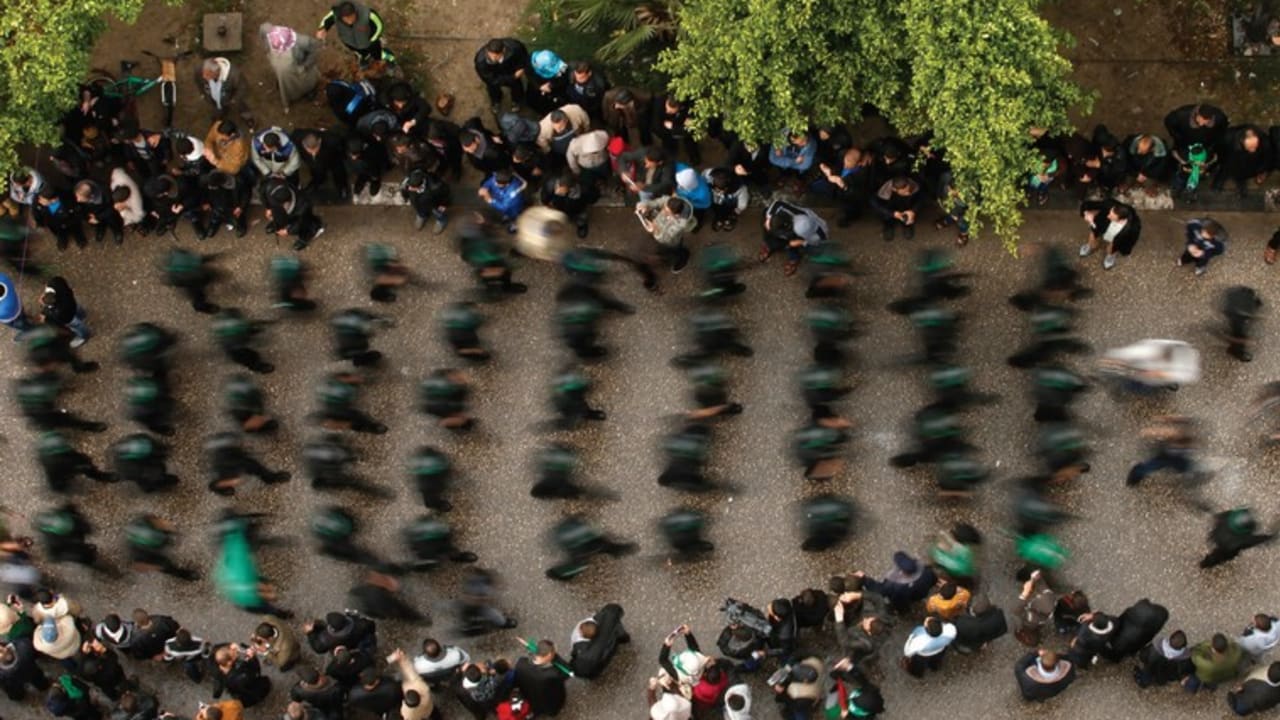 PEOPLE WATCH as Palestinian members of al-Qassam Brigades parade in Gaza
