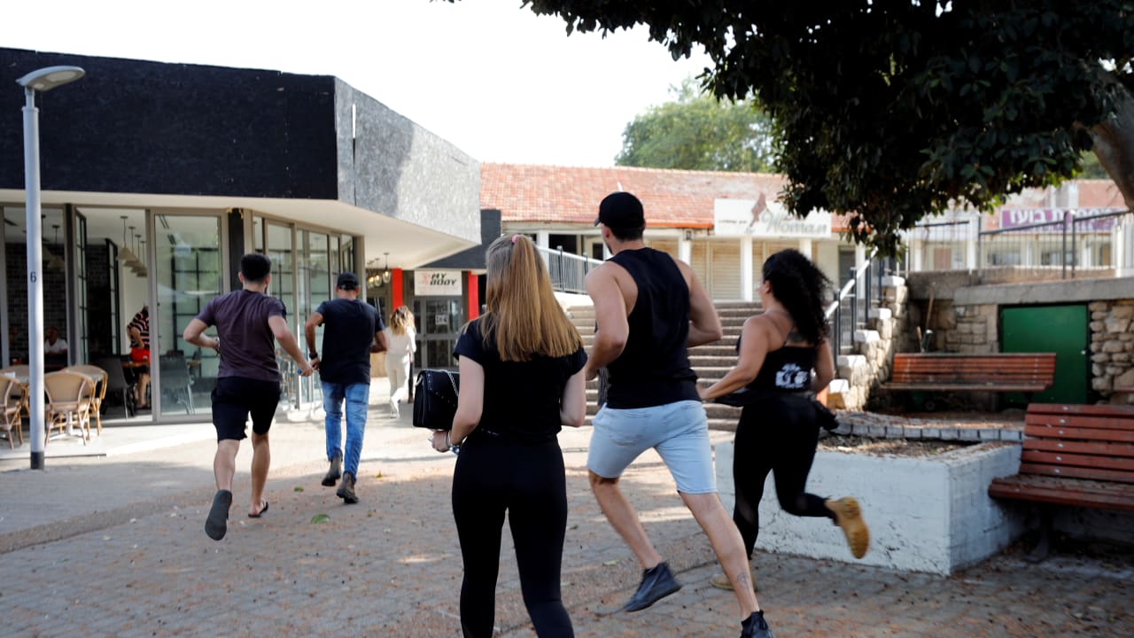 People run to take shelter as a siren warning of incoming rockets sounds in Ashkelon  on November 13