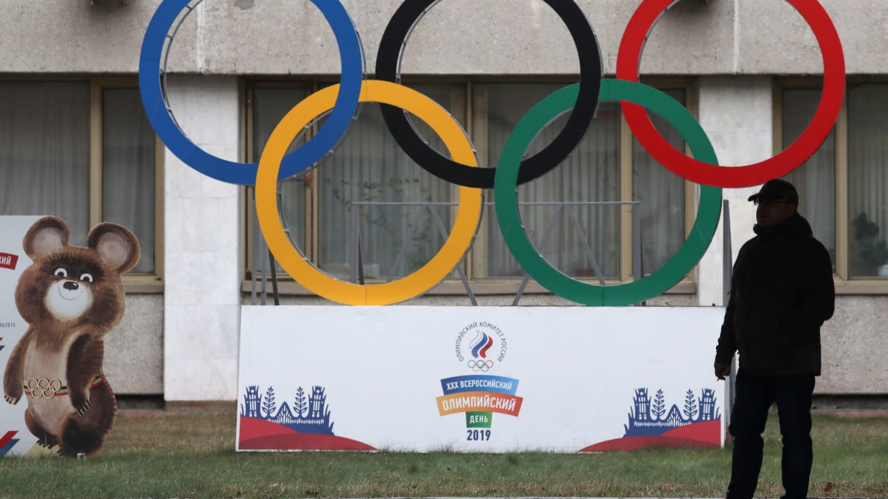 A man stands in front of the Olympic rings outside the headquarters of the Olympic Committee of Russia in Moscow