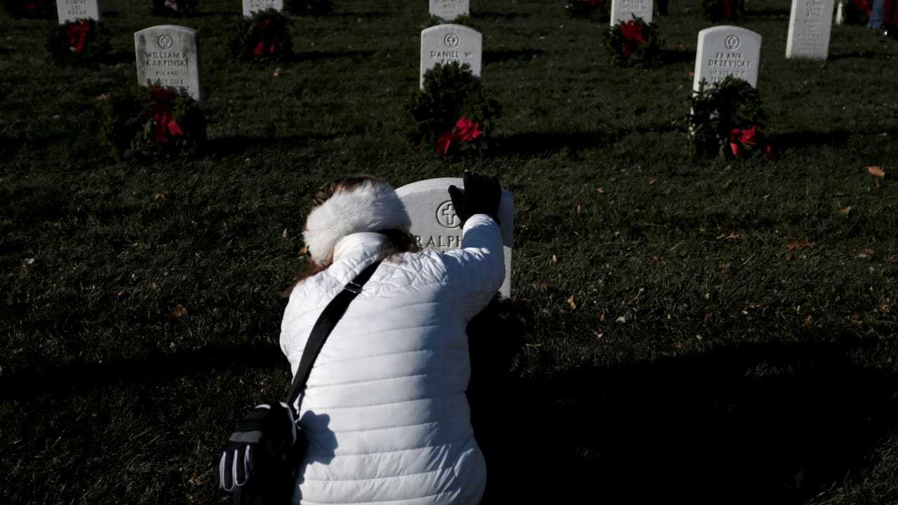 US Army combat veteran Marilyn Pietri of Woodbridge, Virginia places her hand on a headstone as she lays a Christmas wreath at Arlington National Cemetery in Arlington, Virginia, US, December 16, 2017.