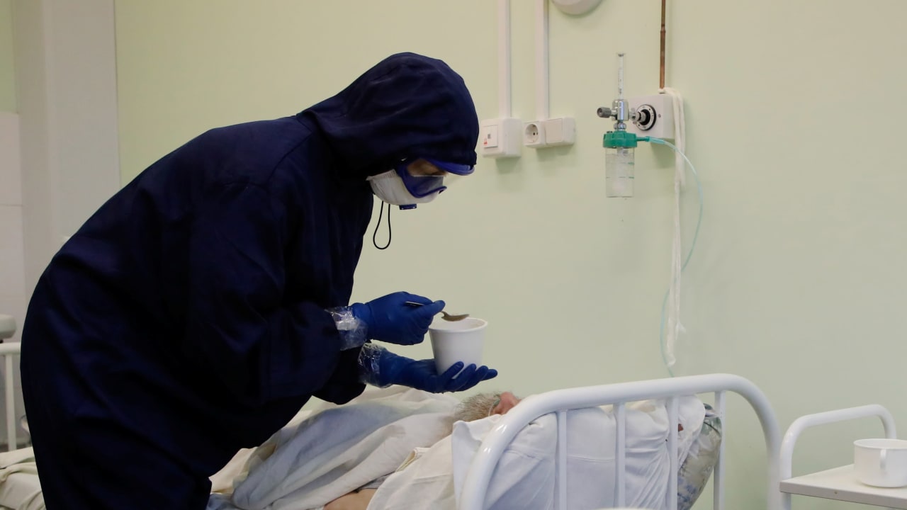 A medical specialist wearing protective gear feeds a patient at the Vologda City Hospital Number 1, where patients suffering from the coronavirus disease (COVID-19) are treated, in Vologda, Russia November 24, 2020.