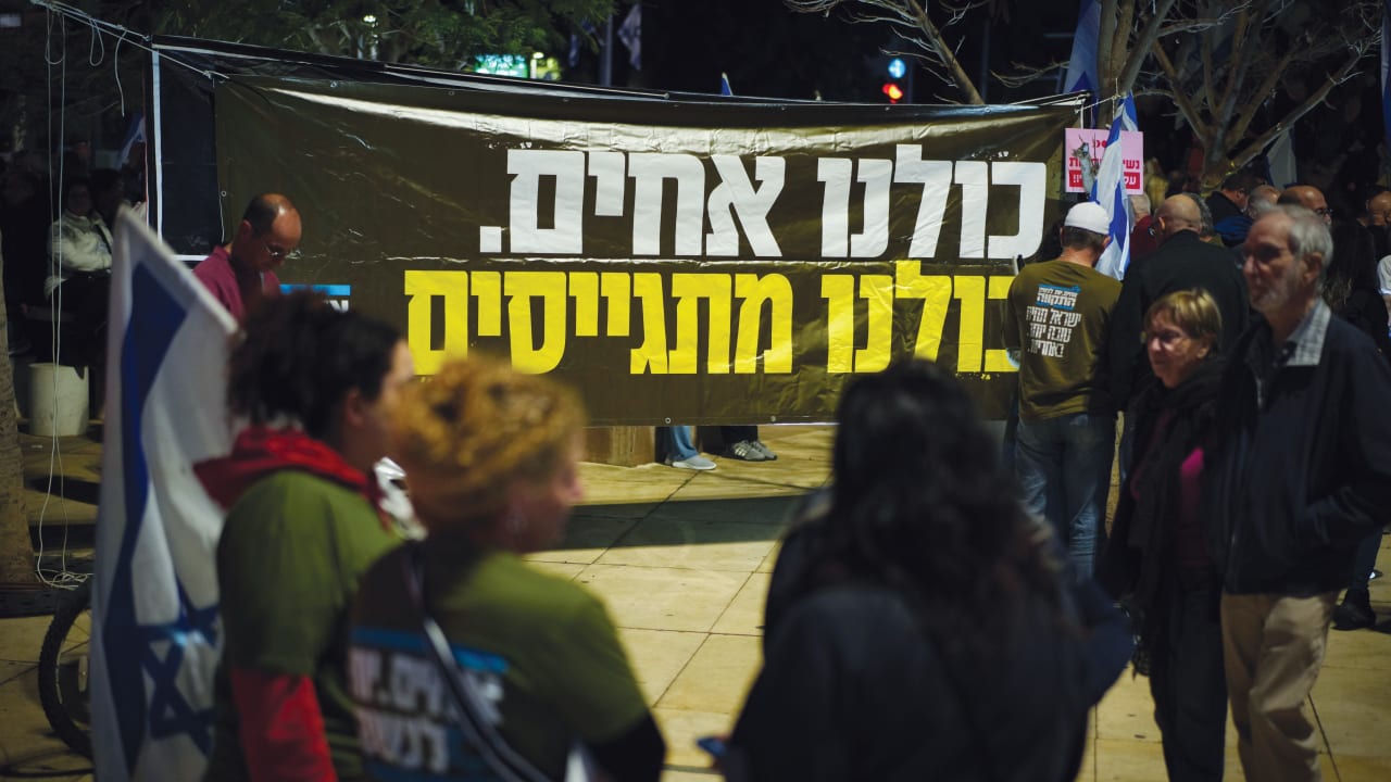  A poster at a Tel Aviv protest reads in Hebrew, "We are all brothers. We are all drafted."