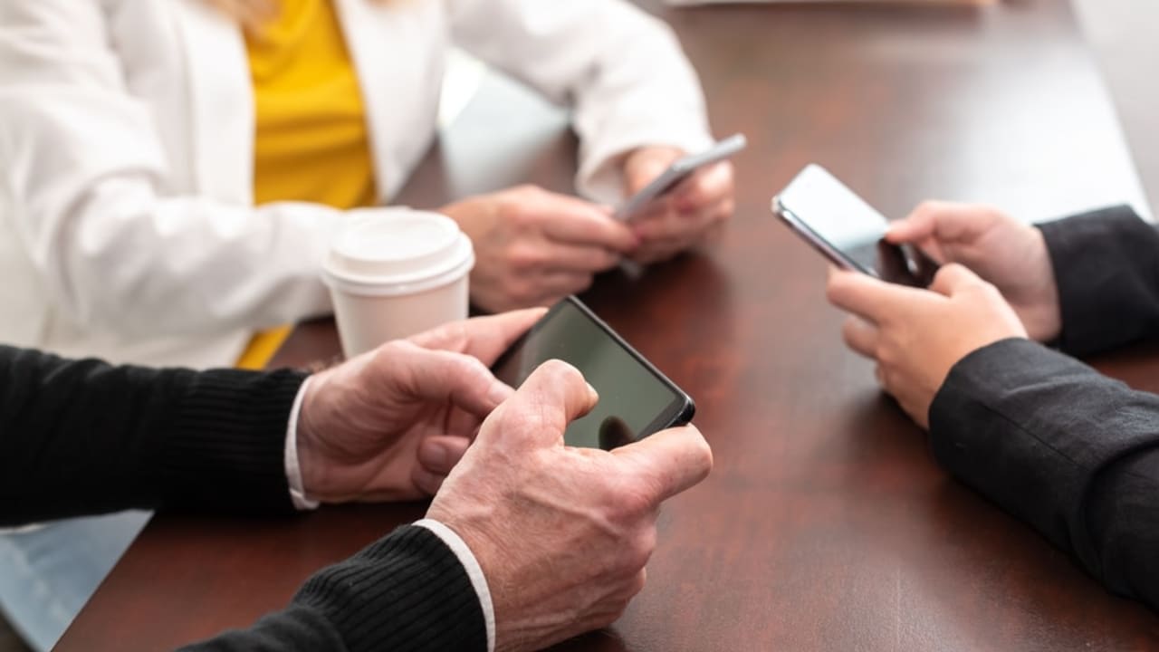 Group of people using and looking at mobile phone together.