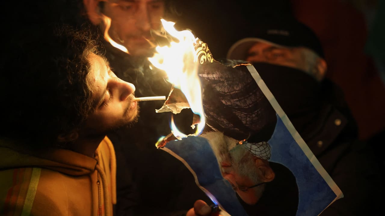 Dos hombres encienden un cigarrillo con una foto en llamas del líder de la República Islámica, Ali Khamenei, mientras la prenden fuego frente a la embajada iraní en Londres, Reino Unido, durante una manifestación celebrada ayer. 