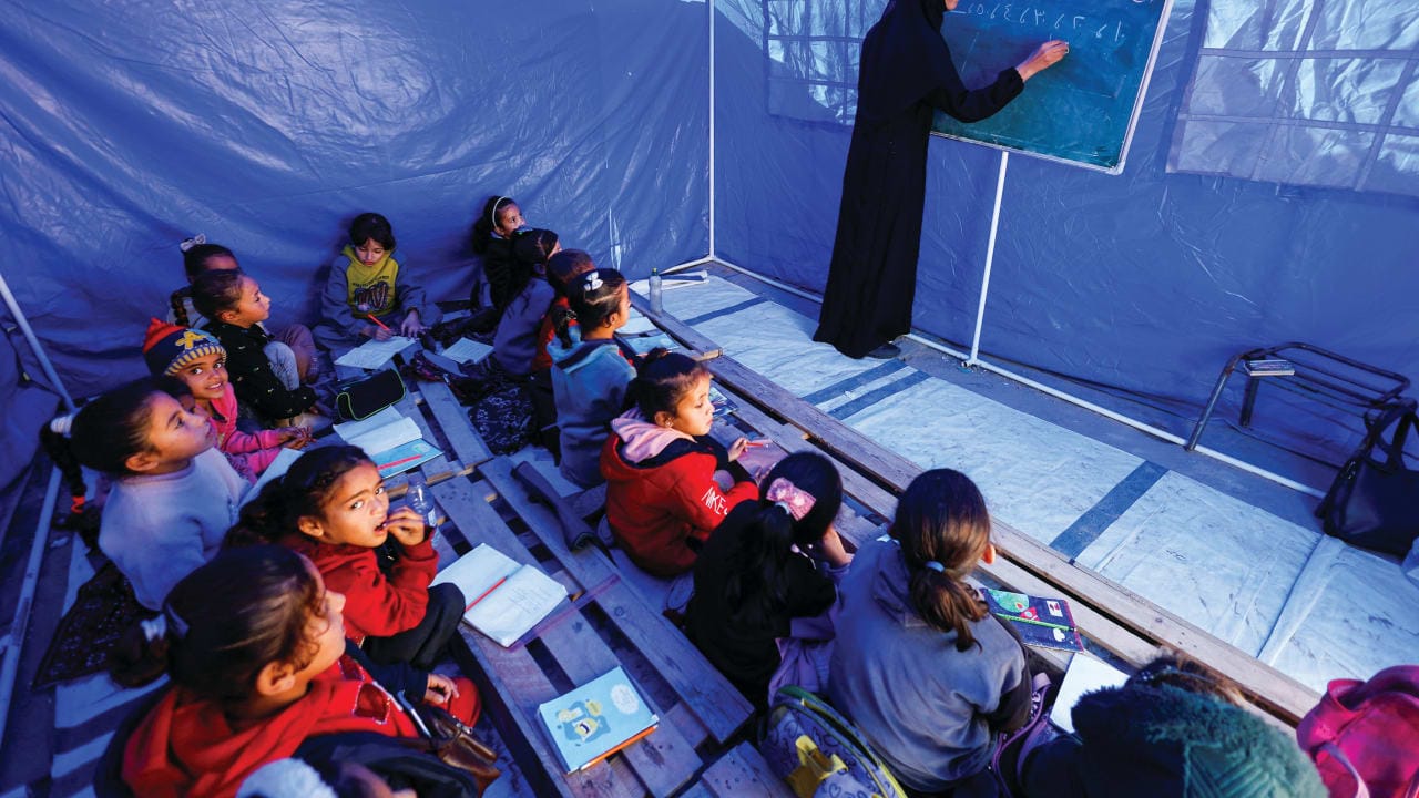 PALESTINIAN CHILDREN study inside a tent in the northern Gaza Strip. Education reform is critical to rebuilding Gaza, the writer says.