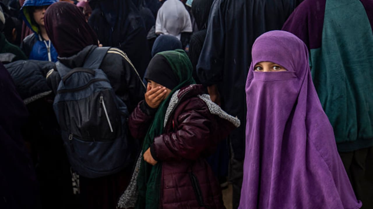 Women and children queue in the rain during a joint security operation by Syria's Kurdish Internal Security Police Force, and the Kurdish-led SDF at Camp Roj where foreign relatives of people suspected of belonging to the Islamic State (IS) group are held, April 5, 2025. 