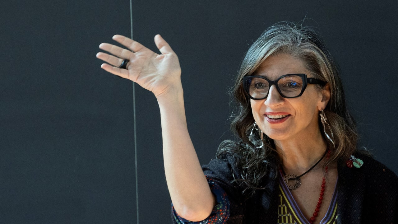 United Nations Special Rapporteur Francesca Albanese waves ahead of a conference.