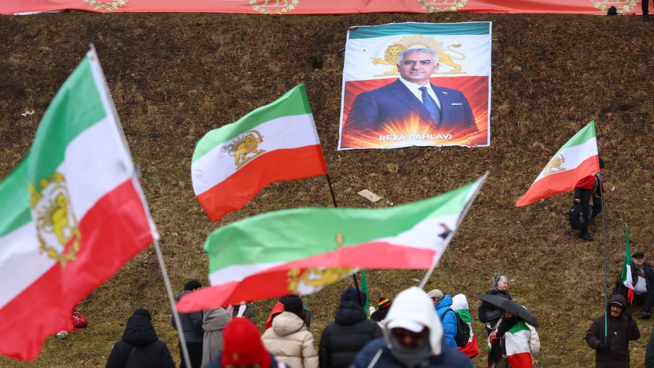 PROTESTERS HOLD ‘Lion and Sun’ pre-Iranian Revolution national flags, near an image of Reza Pahlavi.