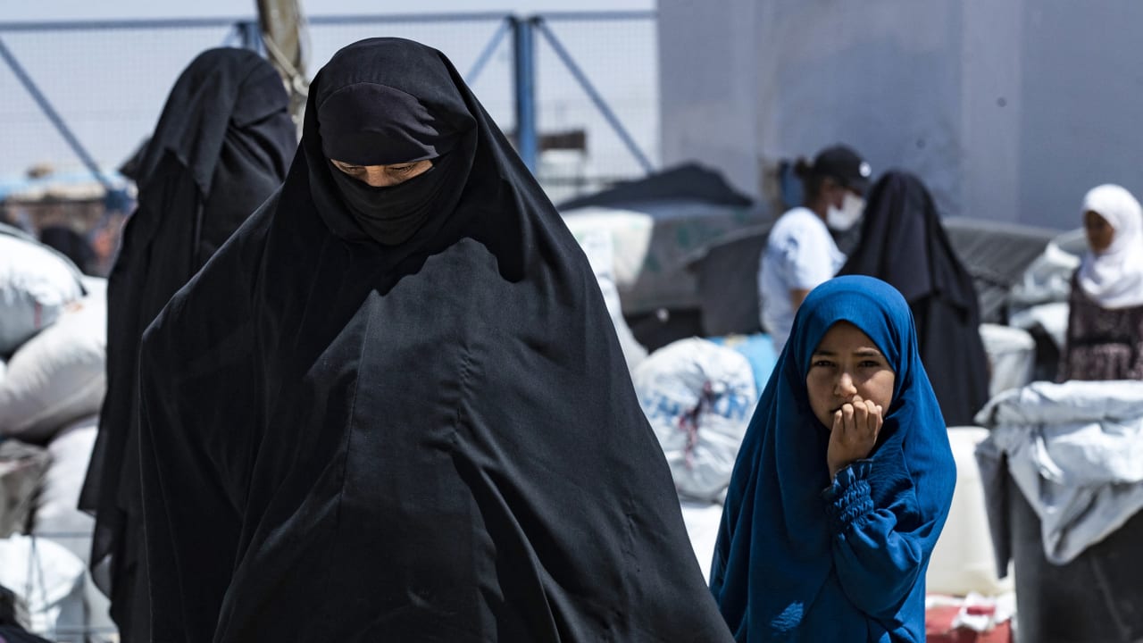 A woman and child walk in the the al-Hol camp in Syria's northeastern Al-Hasakah Governorate on July 28, 2024, as Syrian families of suspected Islamic State fighters prepare to return to their homes in the countryside of Deir Ezzor.