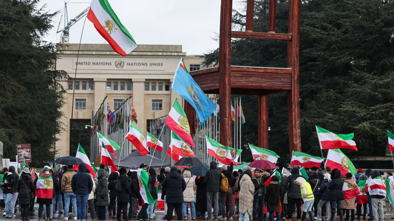 La gente lleva banderas nacionales «León y Sol» anteriores a la Revolución Iraní mientras se reúnen cerca de la oficina de las Naciones Unidas, mientras se celebra la segunda ronda de negociaciones nucleares entre Estados Unidos e Irán, en Ginebra, Suiza, el 17 de febrero de 2026
