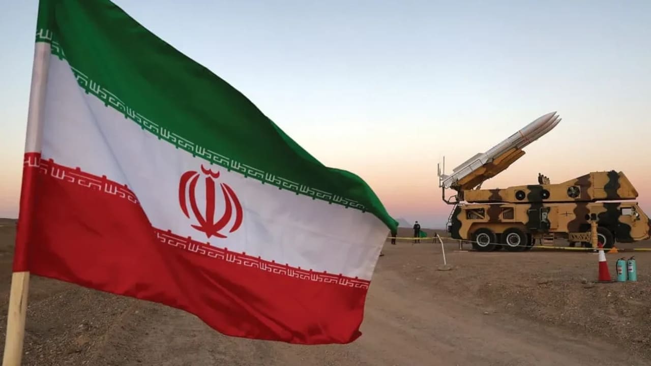 Una bandera iraní aparece cerca de un misil durante un ejercicio militar, con la participación de unidades de defensa aérea de Irán en octubre. 