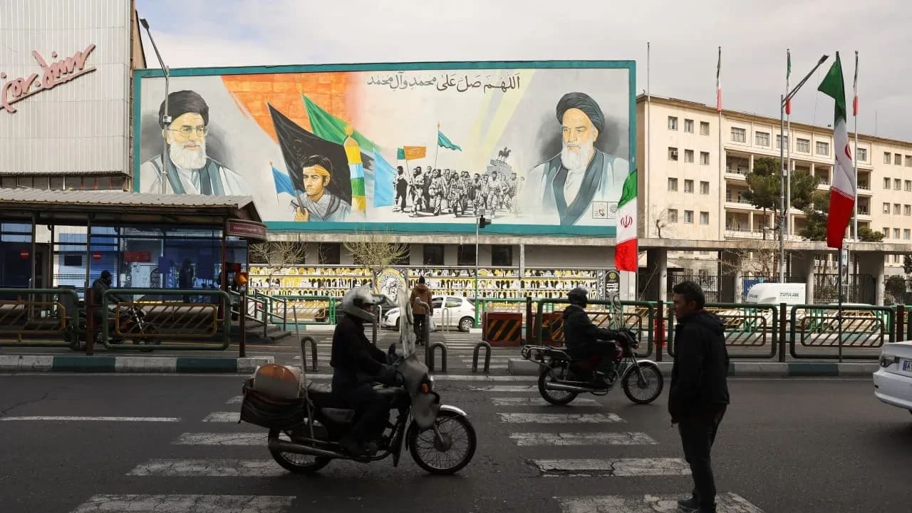 La gente pasa en coche junto a un mural con imágenes del difunto líder supremo de Irán, el ayatolá Alí Jamenei, y del líder de la Revolución Islámica de Irán de 1979, el ayatolá Ruhollah Jomeini, en un edificio de Teherán, Irán, el 2 de marzo de 2026. 