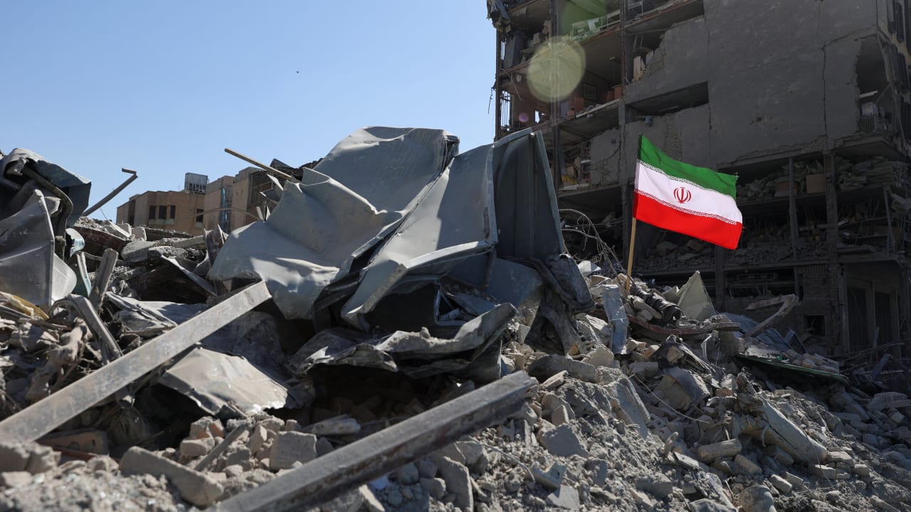 The national flag of Iran flies in the wind as debris lies scattered in the aftermath of an Israeli and US strike on a police station, in Tehran, Iran, March 3, 2026