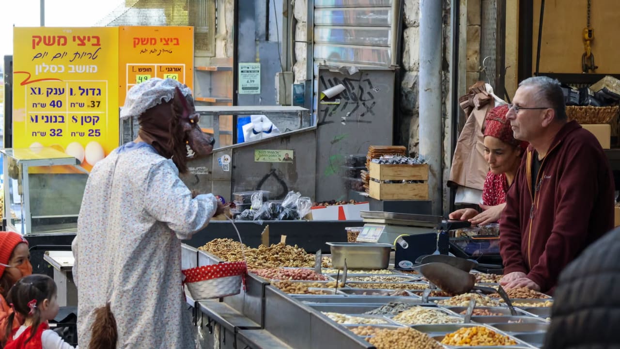 A man wearing a wolf costume with his daughter dressed as Little Red Riding Hood shops at a stall in the Machane Yeduda market in Jerusalem, which was operating at limited capacity because of the war with Iran, during Purim in Jerusalem, March 4, 2026. 