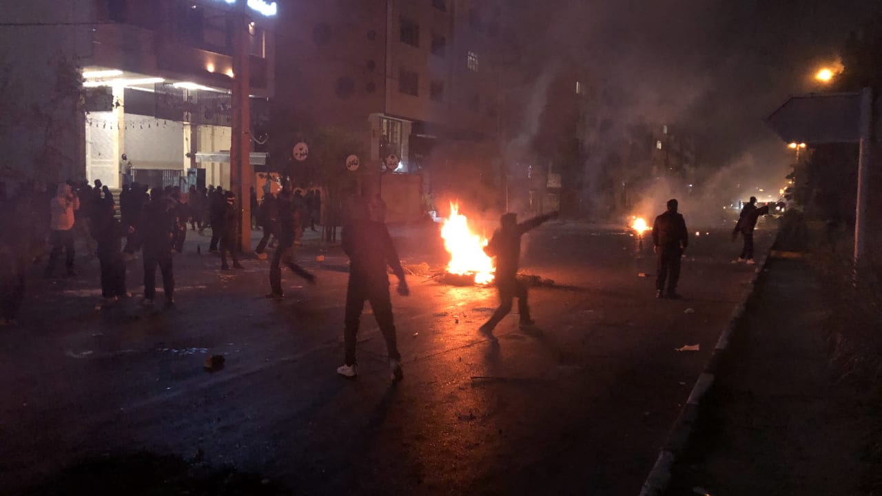 A protester throws a stone near a fire as other demonstrators gather while blocking a street in Shiraz, Iran, on January 10, 2026.