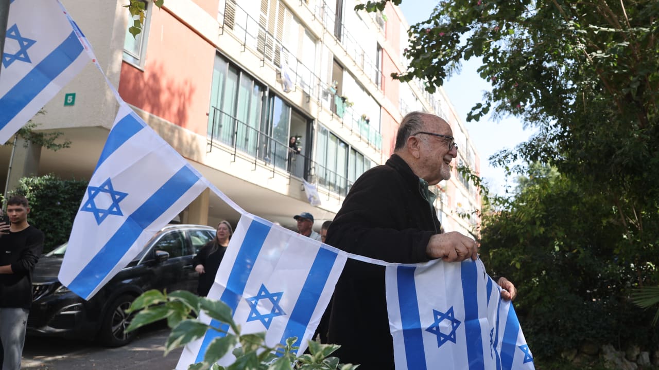 A man brandish Israeli flags following an Iranian strike in Givatayim, in the center of Israel on March 6, 2026. 
