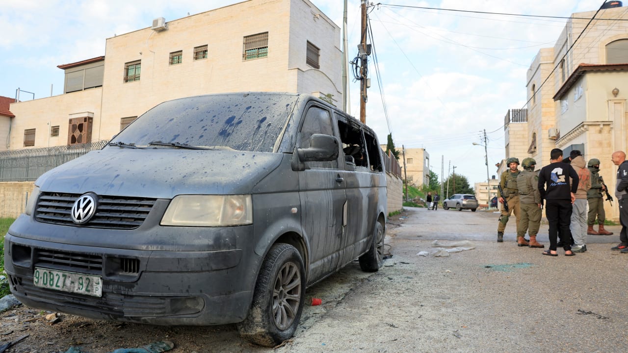 ISRAELI SOLDIERS stand near a vehicle, which Palestinians say was burned by Israeli settlers, in Hebron in the West Bank, March 19, 2026.