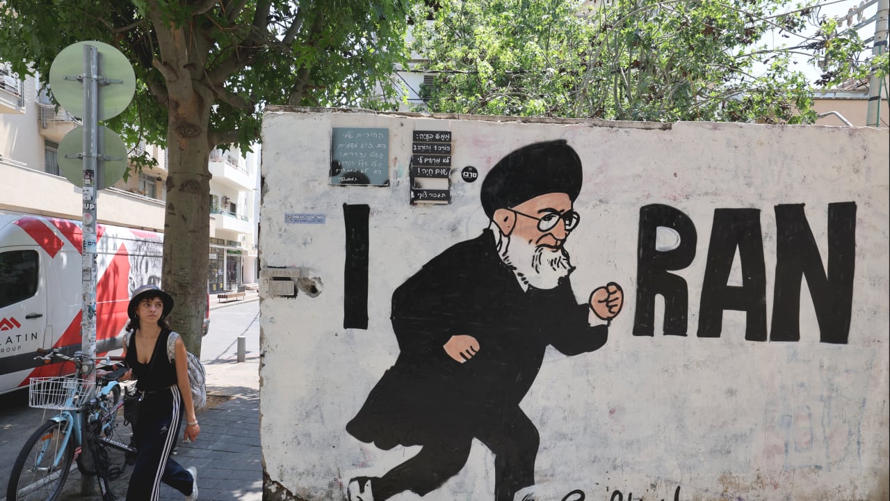 People walk past a mural drawn by the "Grafitiyul" graffiti art group depicting Iran's Supreme Leader Ayatollah Ali Khamenei, on a street in the Israeli coastal city of Tel Aviv on July 22, 2025.