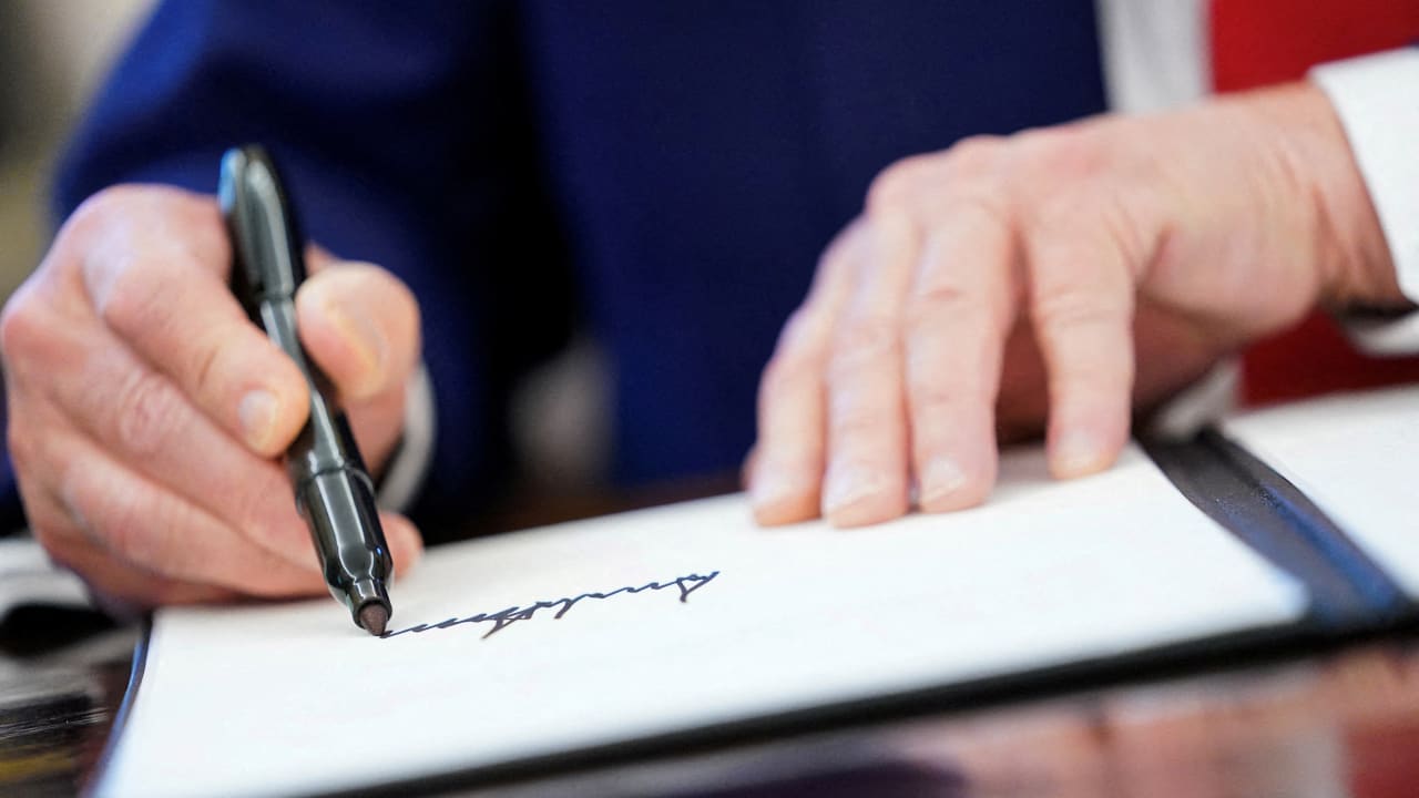 US President Donald Trump writes his signature, as he signs executive orders and proclamations in the Oval Office at the White House in Washington, DC, US, April 9, 2025.