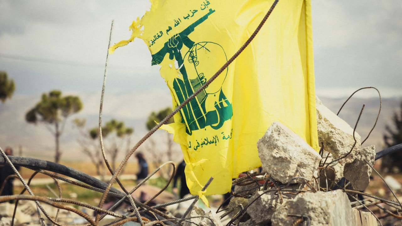 A Hezbollah flag waves among a destroyed building following an Israeli airstrike during a media tour in Baalbek, Lebanon, on March 23, 2026.