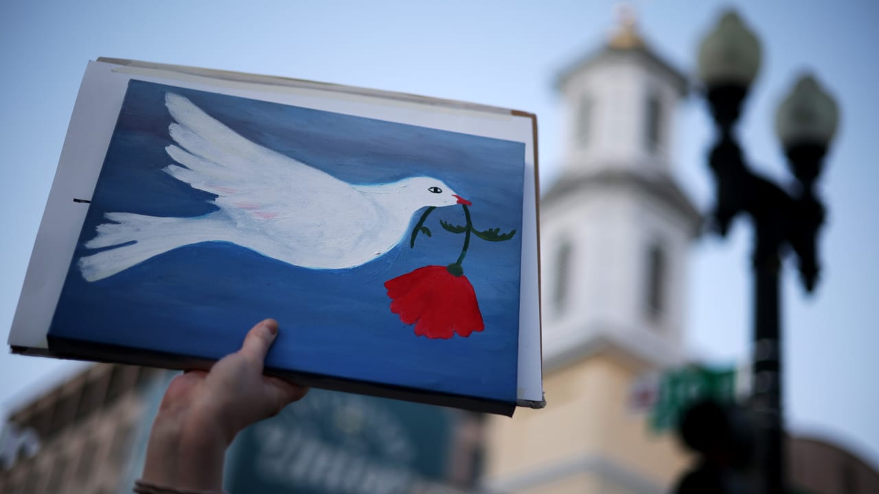 An Anti-war demonstrator holds up a sign with a symbol of peace as they gather near the White House to protest the war in Iran on April 7, 2026 in Washington, DC. 