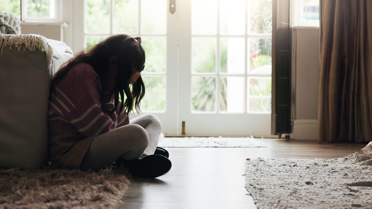 Sad, child and crying on floor in home with mental health, abuse or anxiety from trauma.