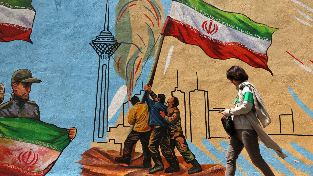 An Iranian woman walks past an anti-USA and anti-Israel mural, in Tehran on April 21 2026, amid a ceasefire in the region. 