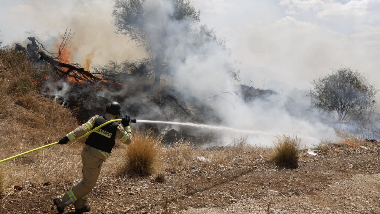 Firefighters douse flames in a field after a drone launched from southern Lebanon fell near Kibbutz Snir in the Upper Galilee.