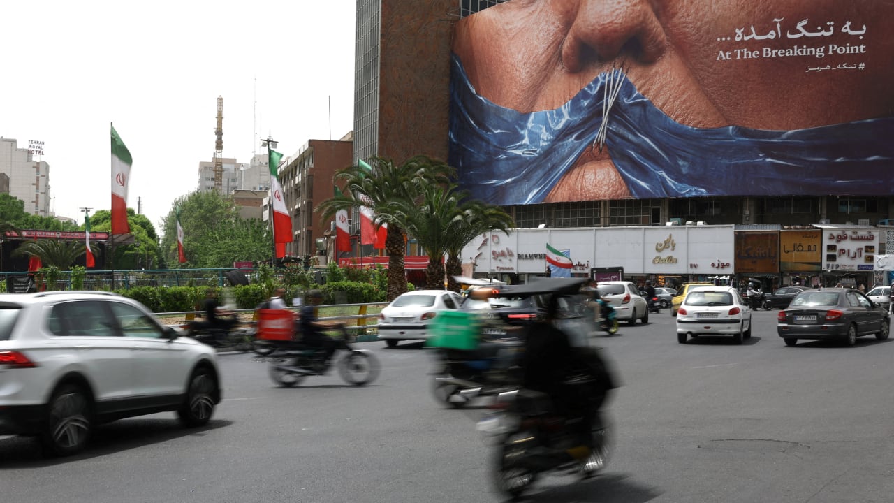 People drive past an anti-US billboard depicting U.S. President Donald Trump and the Strait of Hormuz, in Tehran, Iran, May 4, 2026. 