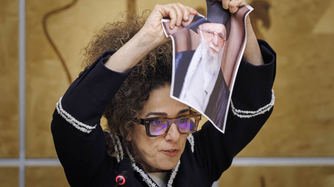 Iranian journalist Masih Alinejad tears a picture of Iran's supreme leader Ayatollah Ali Khamenei as she speaks at the United Nations Offices in Geneva, on February 17, 2026.