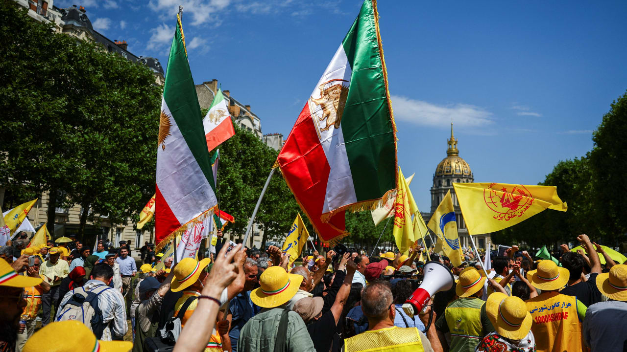 People hold a pre-Iranian Revolution "Lion and Sun" national flag as they attend a demonstration against political executions in Iran and in support of a democratic republic, a demonstration which was banned by Paris Police Prefecture, in Paris, France, June 20, 2026.