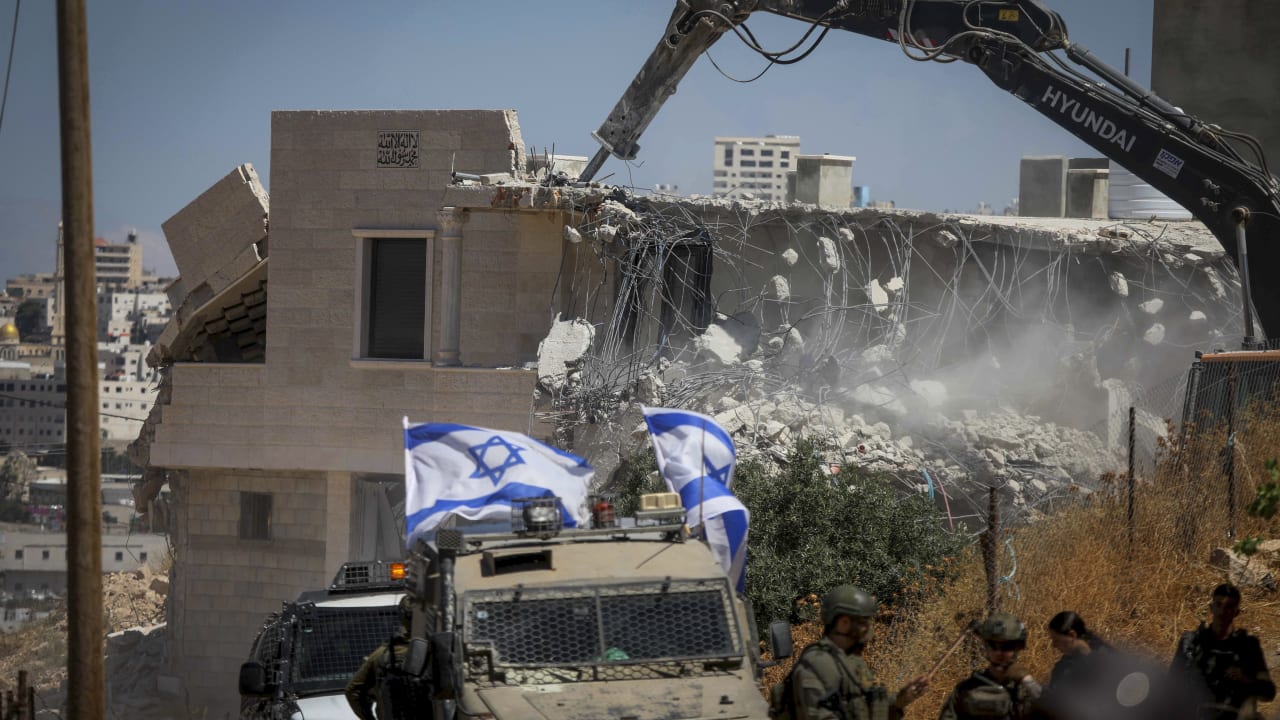 ISRAELI SECURITY forces guard while Israeli bulldozers demolish a Palestinian home in the Khirbet Qalqas area, south of the city of Hebron in the West Bank, June 23, 2026.