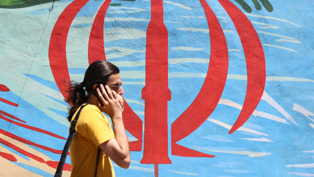 An Iranian man walks past an anti-US and anti-Israel mural painted on a wall, in the capital Tehran on May 10, 2026. 