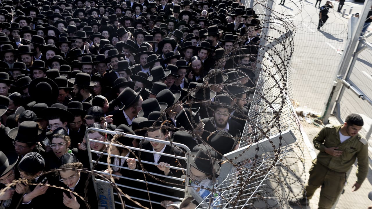 An Israeli soldier guard as young men gathered during a demonstration by Ultra-Orthodox Jews against Israel's military draft on June 17, 2026 outside the Beit Lid military base in Kfar Yona, Israel. The conscription of young ultra-Orthodox men into the military, from which they were long exempt.